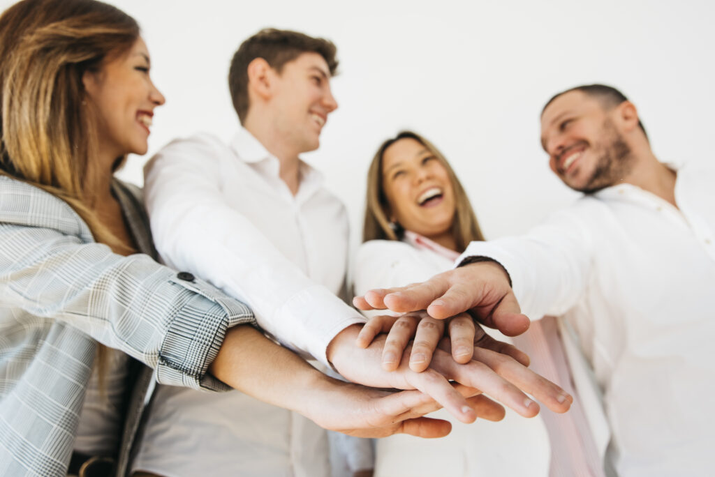 smiling office coworkers putting hands together 1